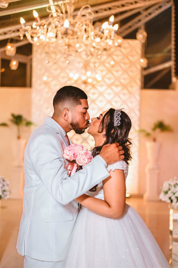 Casal de noivos se beijando com lustre atrás